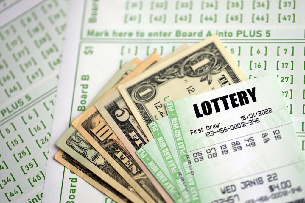 Green lottery tickets and US money bills on blank with numbers for playing lottery close up