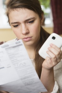 Teenage Girl Studying Mobile Phone Bill Looking Worried