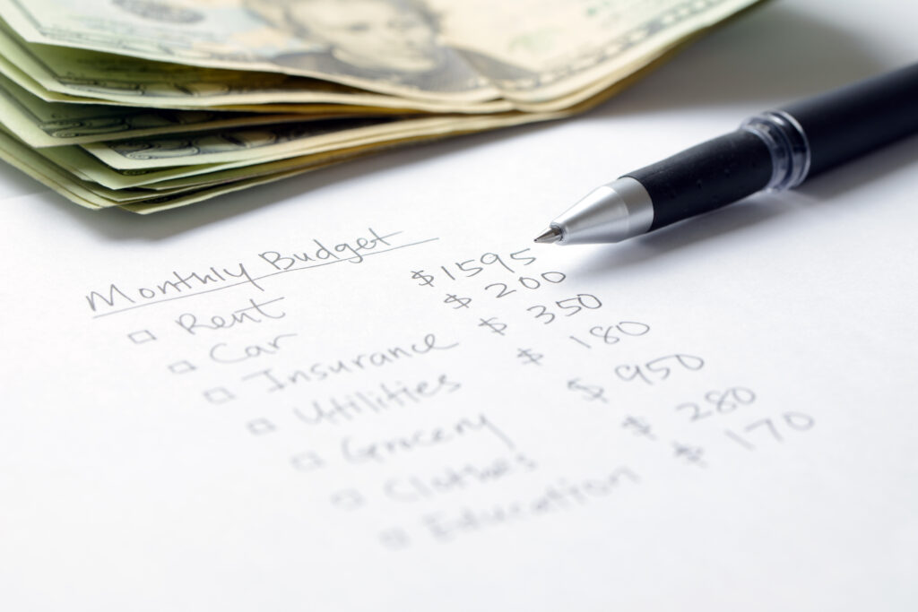 Monthly budget planning sheet with pen and list of monthly expenses